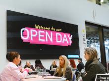 Students speaking to teachers at an Open Day in front of a open day sign