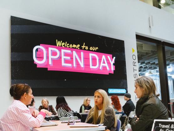 Students speaking to teachers at an Open Day in front of a open day sign